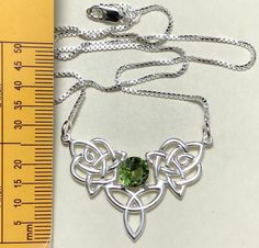 An elegant finish to a popular Celtic knot design and a wonderful gift for her, or yourself, with this simple and elegant boho chic necklace! A Valentine's Day gift, birthday or any special occasion! This piece is fabricated in sterling silver and features a 6mm center faceted gemstone set within the center of the Celtic knot in a 4 prong setting. Also, this comes with an 18 inch sterling silver box chain, 1mm in thickness. The total length of the pendant is 1 inch for a total of 18 inches inclu Elegant Silver Necklace With Green Amethyst, Silver Green Amethyst Gemstones For Gift, Hallmarked Peridot Jewelry For Gift, Celtic Emerald Necklace, Green Sterling Silver Pendant Gemstone, Nickel-free Amethyst Bohemian Jewelry, Boho Chic Necklace, Celtic Knot Designs, Blue Topaz Necklace