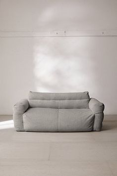 a couch sitting on top of a hard wood floor next to a white brick wall