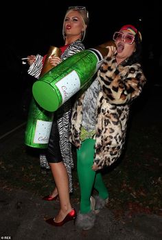 two women dressed in costumes, one holding a bottle and the other carrying a wine bottle