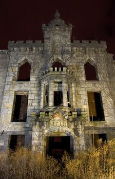 an old stone building with windows and a clock on it's face at night