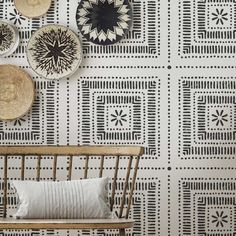 the wall is decorated with black and white geometric designs, which are hanging above a bench