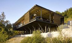 a large wooden structure sitting on top of a hill next to trees and grass covered hillside