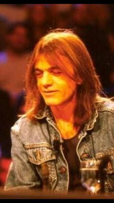 a man with long hair sitting at a table