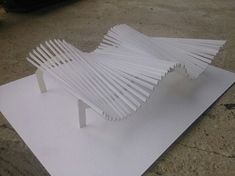 a sculpture made out of white paper sitting on top of a piece of plywood