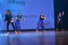 dancers performing on stage in front of an adhata advertisement at the end of their performance