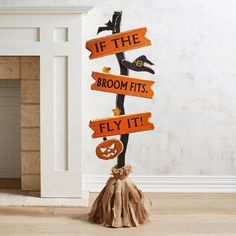 a wooden sign that says if the broom fits fly it on top of a pumpkin