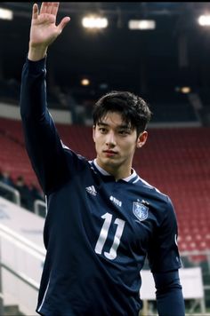 a young man waves to the crowd while standing in front of an empty bleachers