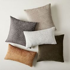 four different colored pillows sitting next to each other on top of a white wall and floor