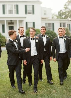 a group of men in tuxedos standing next to each other on a lush green field