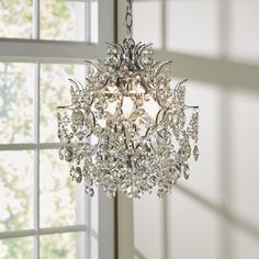 a crystal chandelier hanging from the ceiling in a room with white walls and windows