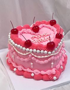 a pink heart shaped cake with cherries on top