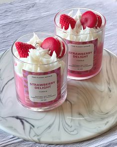 two small cups filled with whipped cream and raspberries on top of a plate