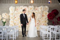 a bride and groom holding hands in front of a floral backdrop at their wedding ceremony