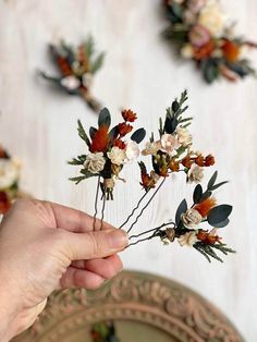 a person is holding some flowers in their hand while they are hanging on the wall