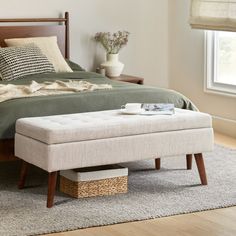 a bed sitting on top of a wooden floor next to a basket filled with pillows