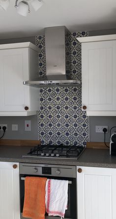 a stove top oven sitting inside of a kitchen next to white cupboards and counter tops