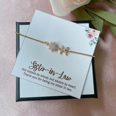 a card that says sister - in - law next to a flower and a bracelet