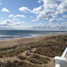 an empty beach next to the ocean under a cloudy blue sky