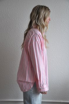 Introducing our Loose Fit Pink Striped Button Down, a stylish and versatile addition to your wardrobe. This button-down shirt features a relaxed, loose fit for ultimate comfort and ease of movement.Crafted from lightweight and breathable fabric, this shirt is perfect for both casual and dressy occasions. The pink stripes add a touch of femininity and sophistication, while the button-down design adds a classic and timeless appeal.The loose fit silhouette makes it easy to style and layer over your favorite tank tops or camisoles. Pair it with jeans or trousers for a chic and effortless look, or tuck it into a skirt for a more polished ensemble.Whether you're heading to the office, meeting friends for brunch, or enjoying a day out, our Loose Fit Pink Striped Button Down is sure to keep you lo Relaxed Long Sleeve Top With Button Closure, Spring Daywear Shirt With Relaxed Fit, Everyday Pink Button-up Shirt, Relaxed Shirt With Button Closure For Daywear, Relaxed Button-up Top, Casual Pink Blouse With Button Cuffs, Relaxed Button-up Tops For Work, Relaxed Button-up Workwear Tops, Pink Button-up Tops For Daywear