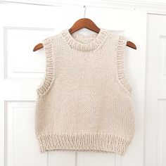 a knitted sweater hanging on a door with a wooden hanger in front of it