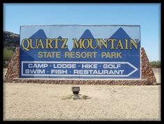 a large sign for the state resort park in front of a dirt field and mountains