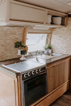 a kitchen area with an oven, sink and stove top in a motorhome