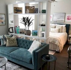 a living room filled with furniture next to a window covered in pillows and blankets on top of a hard wood floor