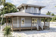 a white house on the beach with palm trees in the background