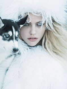 a woman with long blonde hair holding a husky dog