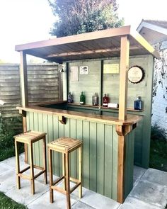 an outdoor bar with two stools next to it