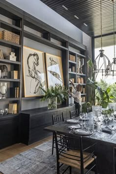 a dining room table set with place settings and chairs, surrounded by bookshelves