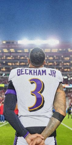 a football player with his hands on his hips looking at the stadium from behind him