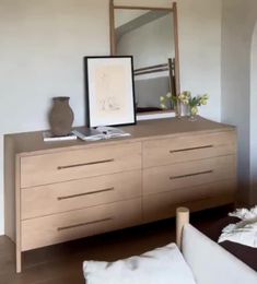 a large wooden dresser with a mirror and vase on it's top, next to a couch