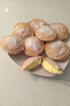 a white plate topped with pastries covered in powdered sugar on top of a counter