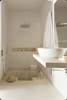 a bathroom with a sink, mirror and shower head mounted to it's wall