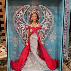 a barbie doll in a blue box with an angel on it's back and red cape