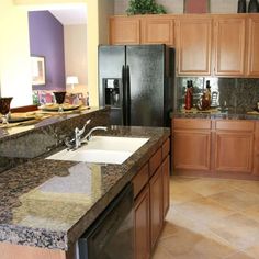 a kitchen with granite counter tops and wooden cabinets, along with black appliances in the background