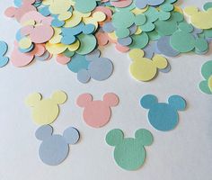 mickey mouse confetti cutouts are scattered on a white surface with pastel colors