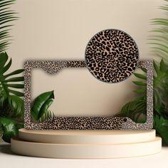 a leopard print cake topper on a white pedestal with plants in the back ground