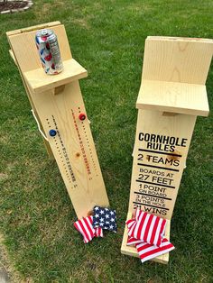 two wooden boards with american flags on them sitting in the grass next to each other