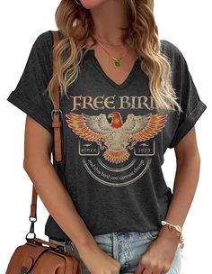 a woman holding a brown purse and wearing a black shirt with the words free bird on it