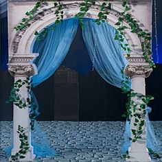 an arch decorated with vines and blue drapes