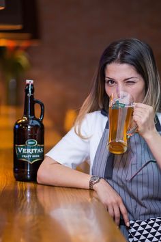 a woman sitting at a bar with a beer