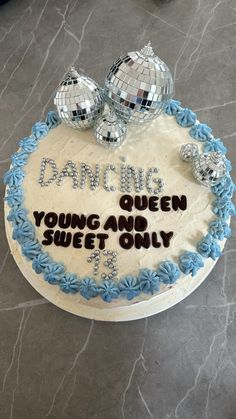 a birthday cake with blue frosting and disco balls on the top that says dancing queen young and sweet only