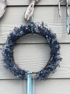 a wreath is hanging on the side of a house with some hooks and an umbrella