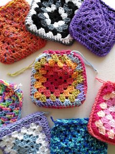 several crocheted grannys are arranged on a white surface, including one in the center