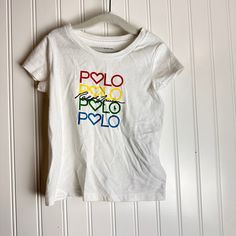 Add A Vibrant Touch To Your Little Girl's Wardrobe With This Polo Ralph Lauren T-Shirt In Size 2t. The Shirt Features A Colorful And Eye-Catching 'Polo' Graphic, Showcasing Her Playful Side While Staying Comfortable And Stylish. It's The Perfect Blend Of High-Quality Material And A Fun Design For Your Toddler. Color White New With Tags Msrp $29.50 Multicolor Graphic Print Tops For Playwear, Casual Multicolor T-shirt For Playwear, Cute Multicolor T-shirt For Playwear, Multicolor Short Sleeve Tops With Logo Print, Multicolor Crew Neck Top For Playtime, Multicolor Cotton Top With Logo Print, Multicolor Fun T-shirt For Playwear, White Fun T-shirt For Playwear, Multicolor Spring T-shirt For Playwear