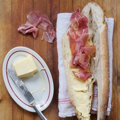 a sandwich with ham, cheese and butter on a plate next to a knife and fork