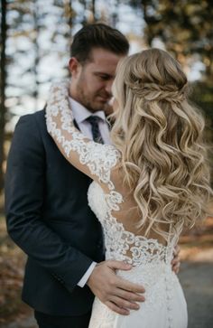 a bride and groom embracing each other in the woods