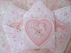 three heart shaped doily sitting on top of a pink and white bed spreader